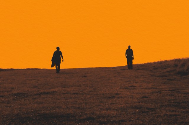 Silhouette of two people on a hill