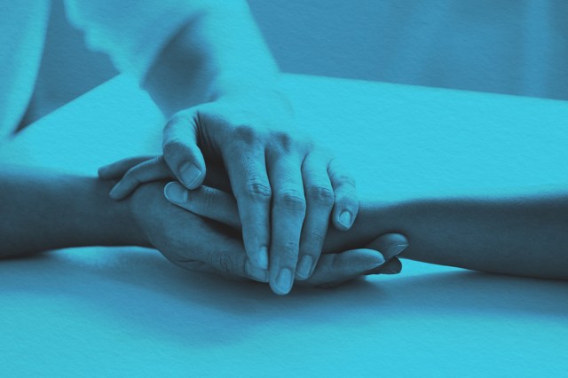 Two people holding hands in effort of support or care