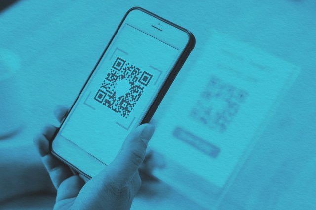 man's hand scanning QR code through mobile phone