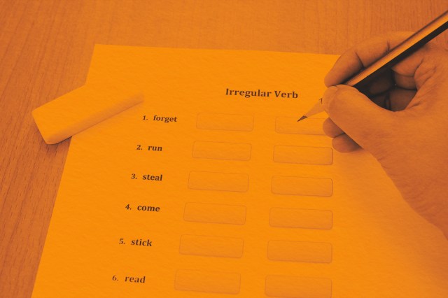 hand holding pencil over irregular verbs exercise