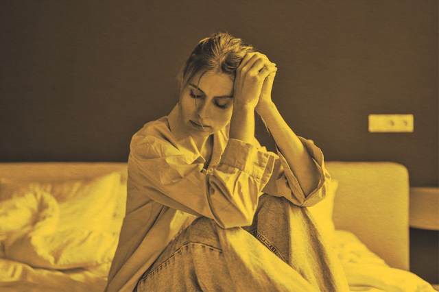 unhappy woman sitting on bed at home