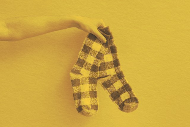 Holding out a pair of socks on solid background