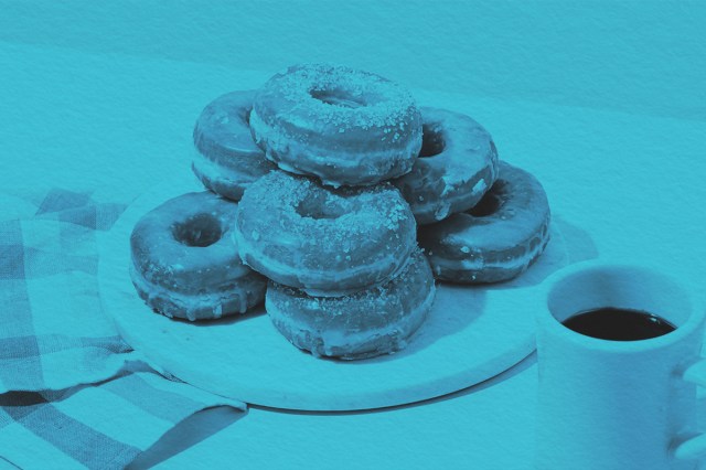 Stack of donuts on a table next to a cup of coffee
