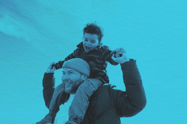 A waist-up shot of a young boy on top of his father's shoulders