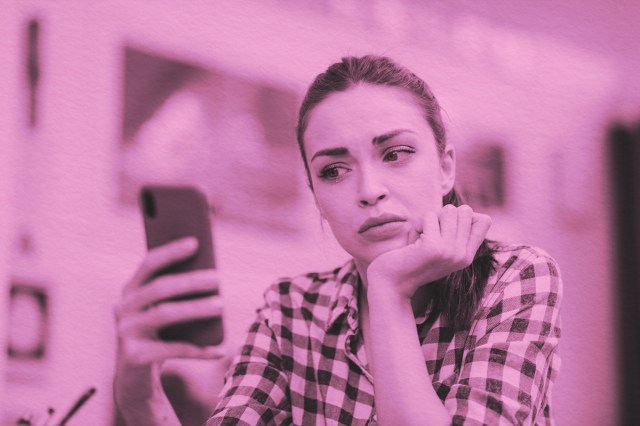 Woman reading text of phone with confused facial expression