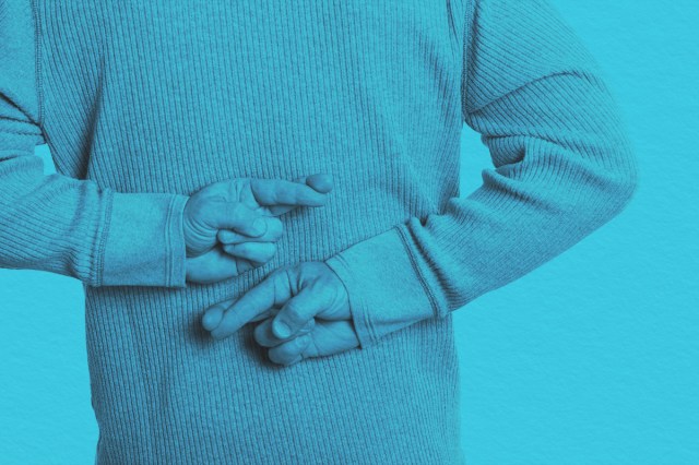 Man crosses his fingers with both hands behind his back